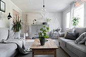 Grey sofas, wooden coffee table and houseplants in living room