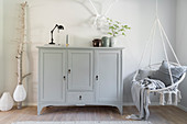 Tall sideboard painted grey and hanging chair in living room