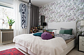 Double bed in bedroom with floral wallpaper