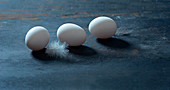 Three hen's eggs on a dark surface