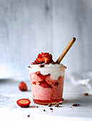 Erdbeereis serviert mit frischen Erdbeeren, Sahne und Schokolade im Glas