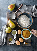 Top view of ingredients and products for preparing sweet pear cake arranged on wooden board
