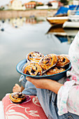A woman holding a plate of blueberry buns with sugar nibs