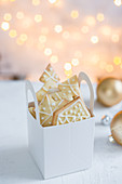 Verzierte Weihnachtsplätzchen in Papierkörbchen als Geschenk
