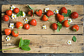 strawberries with leaves and flowers on a wooden board