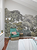 Green armchair against wallpaper with tree motif in bedroom