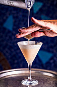 Cocktail Gin Alexander wird in Glas gesiebt