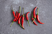 Red chilli peppers on a grey surface (seen from above)