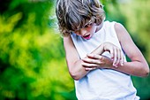 Young boy scratching arm