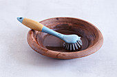 A tagine being cleaned with water and a washing up brush