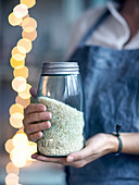 A woman holding a storage jar full of risotto rice