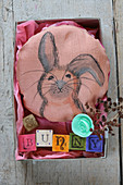 A homemade cushion with a rabbit motif in a box for Easter