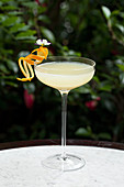 Elaborate orange garnish with a flower on the side of a cocktail