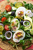 Wraps with deviled eggs, micro herbs, avocado and tomatoes (close up)