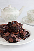 Brownies auf Teller, im Hintergrund Teekanne und Teetasse