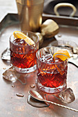Two old fashioned cocktails in cut glasses with mixing equiptment