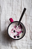 Yogurt with berries in a cup on a white tablecloth