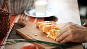 A person cutting a croissant on a board