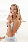 Blonde Frau mit Eis im Bikini am Strand