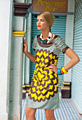 A young woman wearing a patterned summer dress and fashionable jewellery