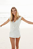 A blonde woman on a beach wearing a long top