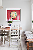 Dining table and country-house chairs below framed poster