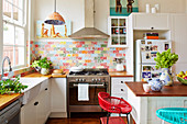 White fitted kitchen with wood worktop wood and colorful wall tiles