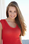 A young blonde woman on a beach wearing a red summer dress