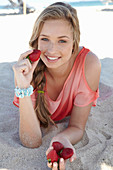 A young blonde woman on a beach wearing a salmon-coloured, off-the-shoulder top