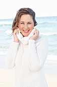 Brünette Frau in weißem Strickpullover am Strand