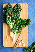 Silverbeet leaves trimmed with a knife on a chopping board
