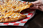 Gournet-Pizza mit Käse auf karrierter Serviette (Nahaufnahme)