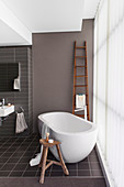 Bathrooms in brown tones, free-standing bathtub in front of polycarbonate wall