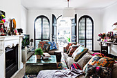 Sofa with colorful cushions and coffee table in front of fireplace, open arched door in background