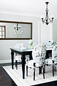 Elegant dining area: dark table, chairs with covers and wall mirror