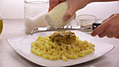A woman making spiral pasta with Pesto Rosso