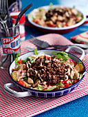 A burger bowl with gherkins and tomatoes