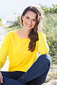 A brunette woman wearing a yellow jumper and jeans