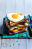 A double-decker toasted sandwich with steak and a fried egg