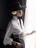 Junge brünette Frau in spanischen Outfit mit Hut steht an Fenster