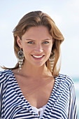 A young brunette woman on a beach wearing a black-and-white striped top