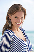 Junge brünette Frau im gestreiften weiß-schwarzen Top am Strand