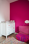 Weiße Kommode mit Wickelauflage und Sitzsack im Zimmer mit pinkfarbener Wand