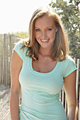 A young blonde woman outside wearing a light-blue top