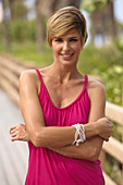 A mature blonde woman with short hair outside wearing a purple top