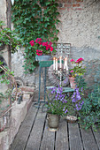 Vintage-style arrangement of potted plants, candles and wreath on terrace