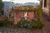 Brunnen an bewachsener Ziegelmauer im Garten