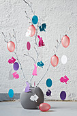 Vase of branches decorated with paper cut-outs and Easter eggs