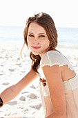 Junge brünette Frau im beigen Shirt am Strand
