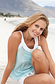 Junge blonde Frau im hellblauen Top am Strand